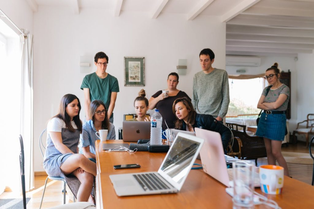 group-of-people-watching-on-laptop-1595385 Group of young professionals engaged in a collaborative meeting in a modern office setting.