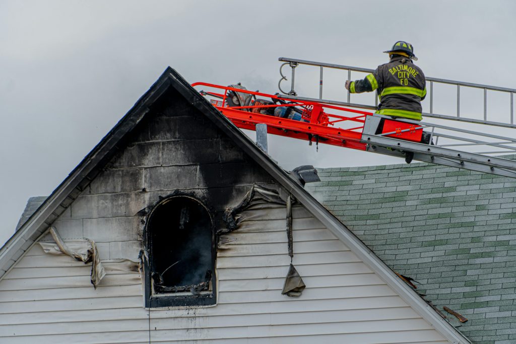 pexels photo 6357619 6357619 Firefighter on ladder tackling a residential roof fire in Baltimore city.